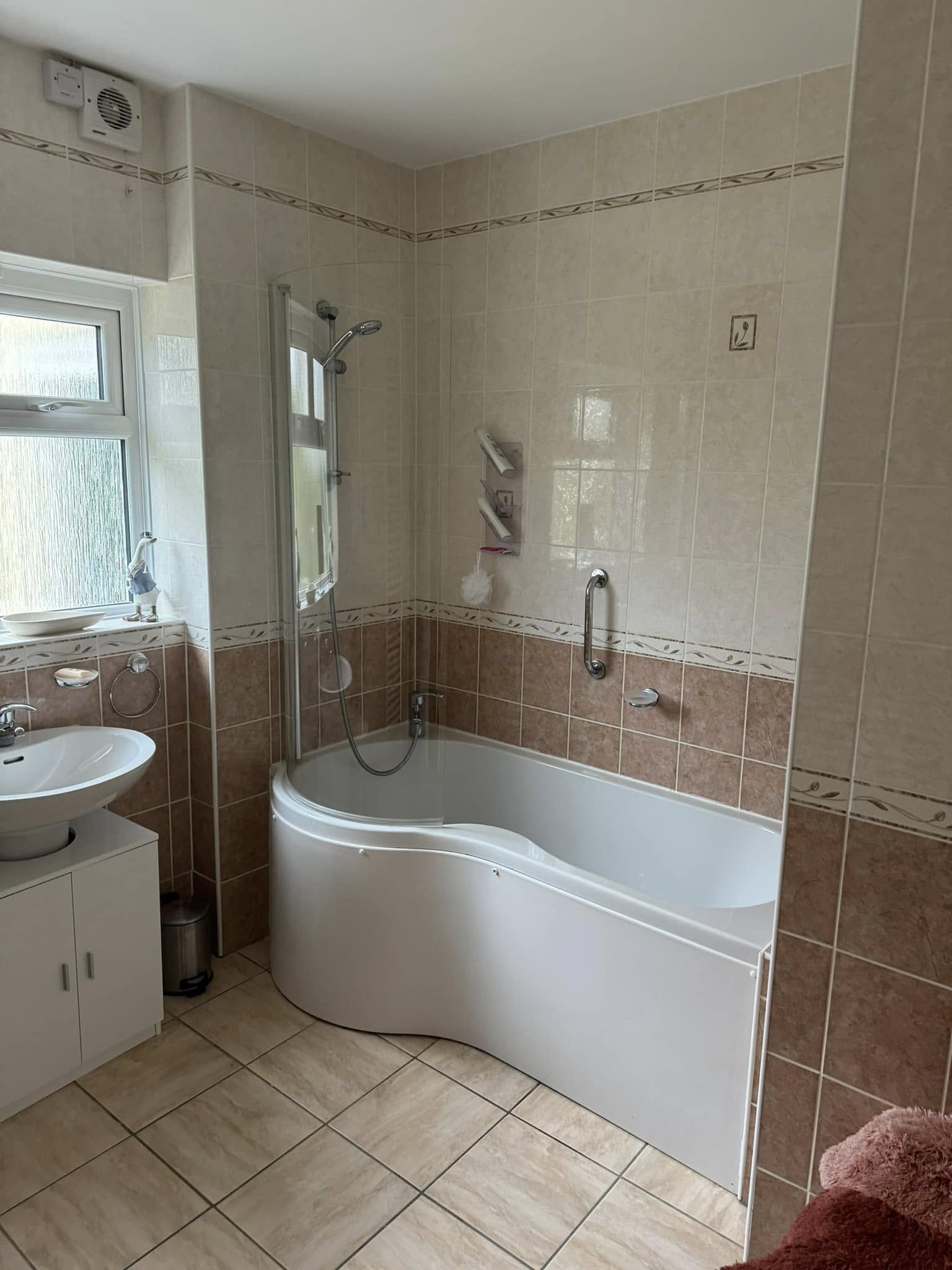 Completed tiled bathroom with a P-shaped shower bath installed by MT Plumbing Services